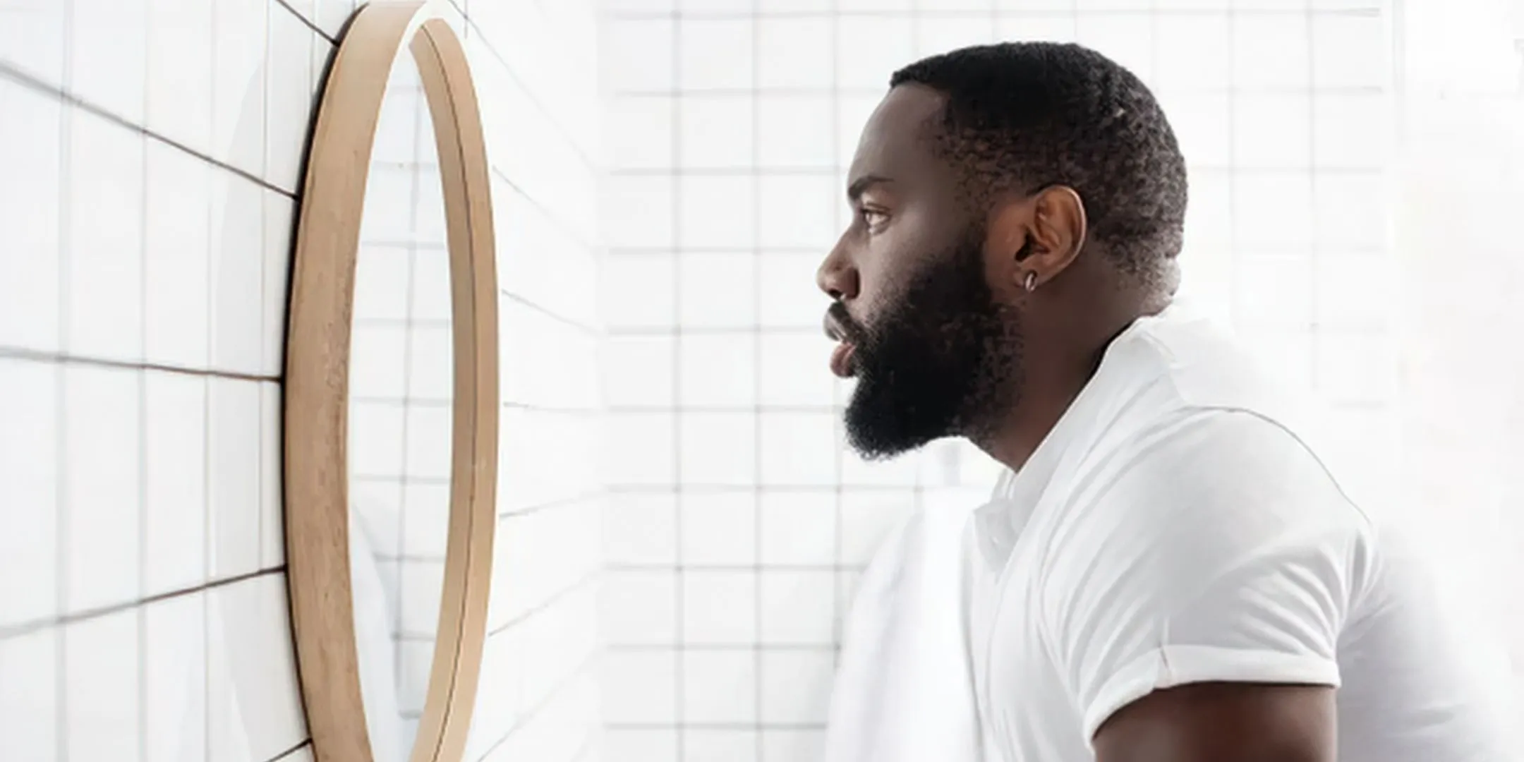  A person stands in front of a mirror, looking at their reflection. 