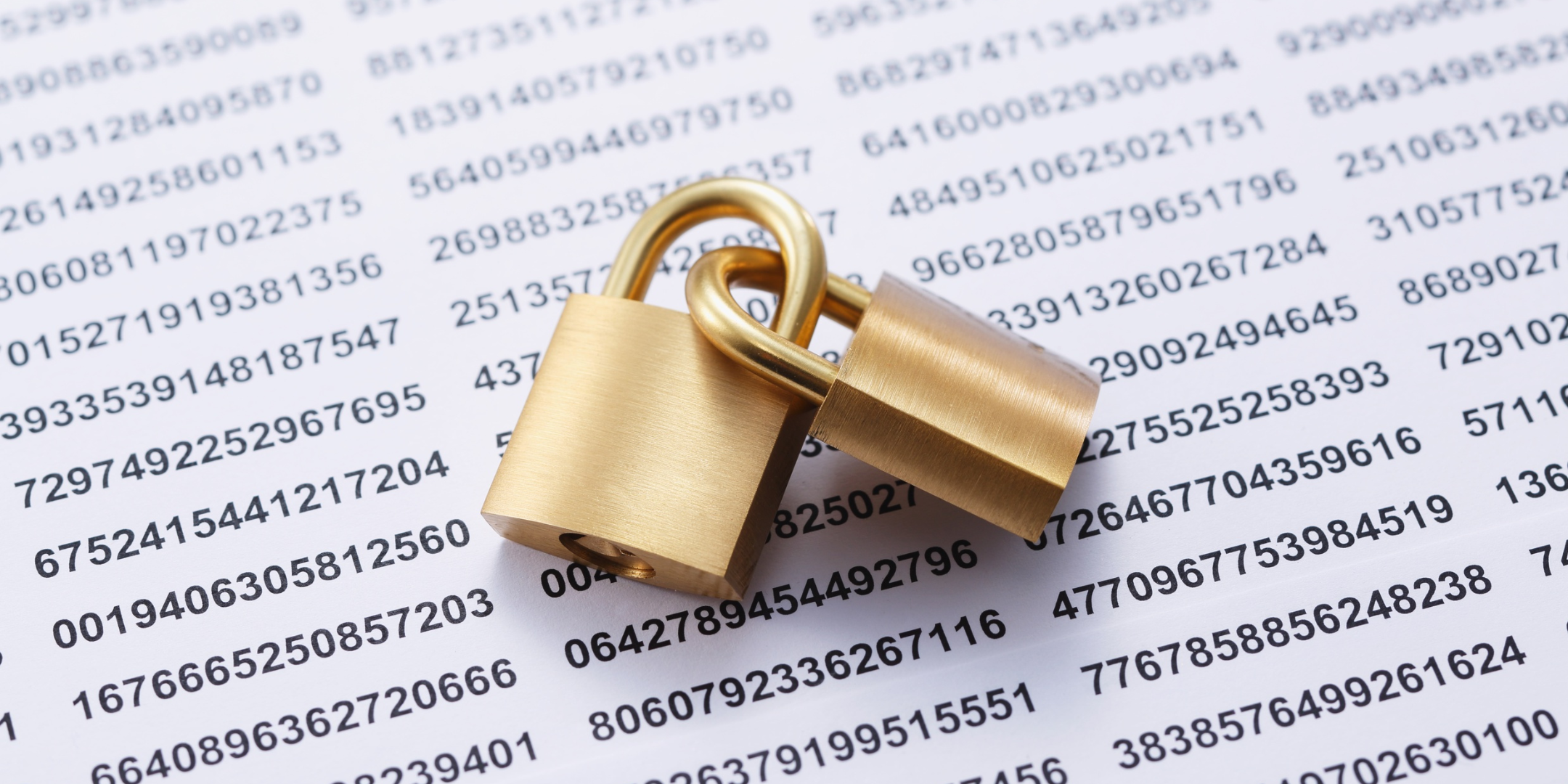 Two brass padlocks resting on a background of printed numbers, representing data security and privacy.